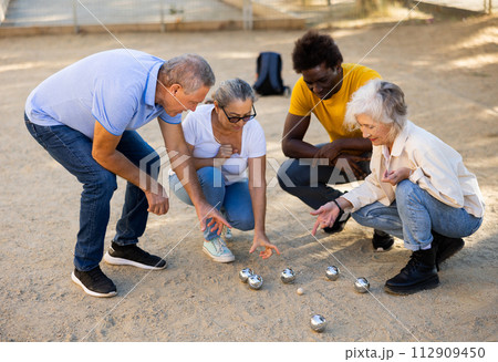 Mature people playing petanque on sand together 112909450