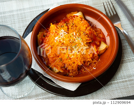 Delicious pasta cannelloni with meat and tomato sauce served in clay plate. Traditional Italian dish 112909694