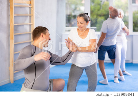 Old woman twisting her opponent's arm during self-defense classes Old woman twisting her opponent's arm during self-defense classes 112909841