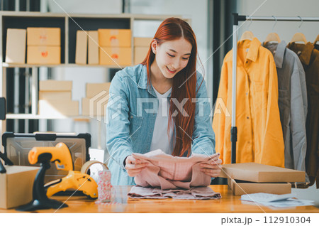 Online small business owners are packing their ordered products that customers order online into a box .concept of online shopping. 112910304