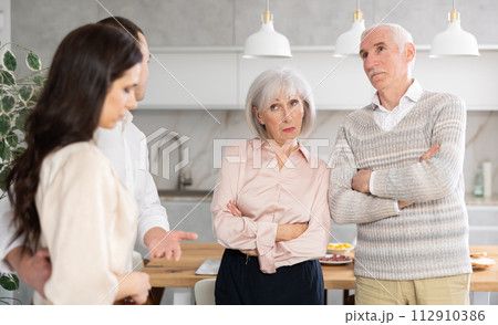 Young guy introducing his girlfriend to his discontented parents at home Young guy introducing his girlfriend to his discontented parents at home 112910386
