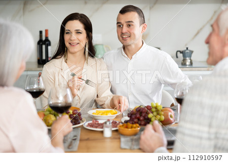 Young couple talking with aged parents at family celebration 112910597