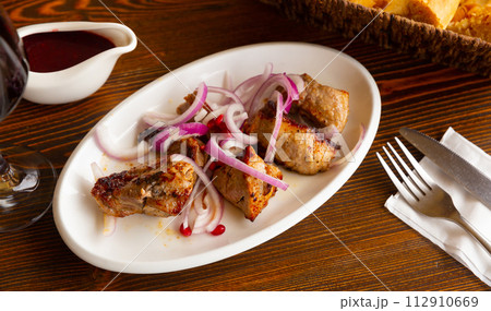 Grilled pork meat shashlik with sliced onion 112910669
