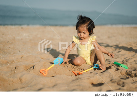 happy toddler baby girl playing sand toy on sea beach 112910697