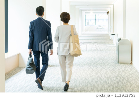 歩くビジネスマンとビジネスウーマンの後ろ姿 112912755