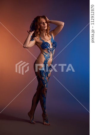Naked woman with blue body paint art in studio 112912870