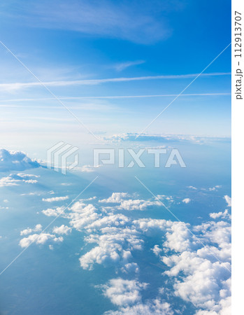 Aerial view from airplane window above green ground. View from the airplane window with beautiful clouds at sunrise 112913707