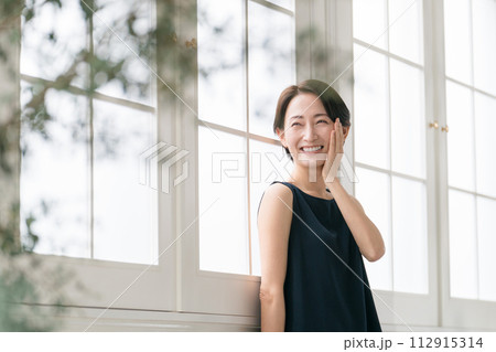 窓際に立つ美しいミドル女性 112915314