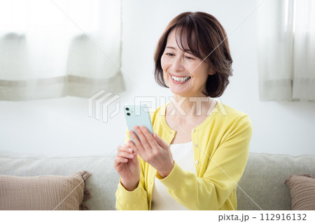 リビングでスマホを操作するシニア女性 112916132