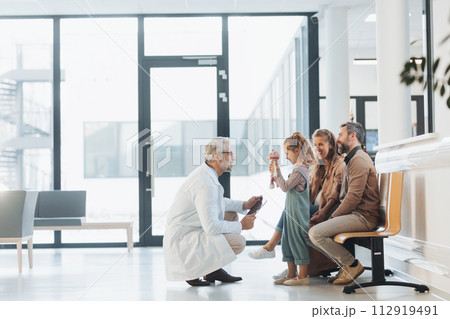Doctor explaining test results to parents of young girl patient, delivering good news. Diagnosis of diseases and head injuries. Doctor explaining test results to parents of young girl patient, delivering good news. Diagnosis of diseases and head injuries. 112919491