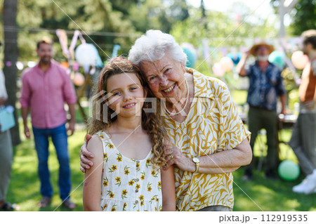 Portrait of girl with grandmother at garden party. Love and closeness between grandparent and grandchild. Portrait of girl with grandmother at garden party. Love and closeness between grandparent and grandchild. 112919535