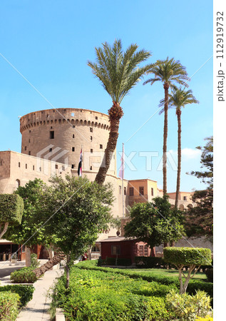 Watch tower, fortress wall and palm trees in ancient Cairo Citadel, Egypt, North Africa. Famous landmark of Cairo - ottoman era Citadel 112919732