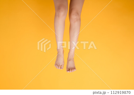 delightful touch of elegance through a 30s person's close up, featuring velvety foot touch on a vibrant yellow backdrop. 112919870