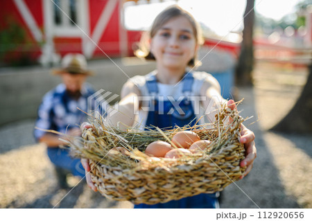 Beautiful young girl helping on family farm during summer, holding lavender plant in pot. 112920656