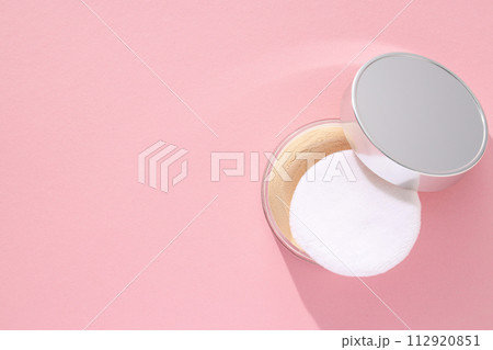 A bottle of powder, light shade, on a pink background. 112920851