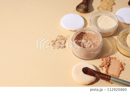 Bottles of face powder, different shades, on a pastel background. 112920860