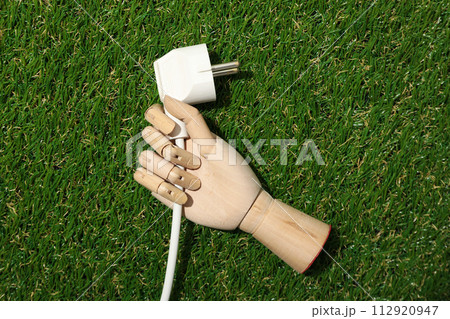 Electric cable in the hand of a mannequin on the grass Electric cable in the hand of a mannequin on the grass 112920947