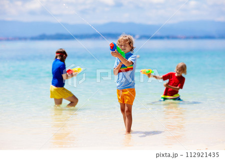 Child with toy water gun. Kids vacation beach fun. 112921435