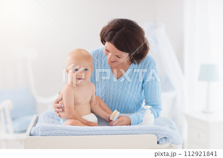 Mother changing diaper to baby boy Mother changing diaper to baby boy 112921841