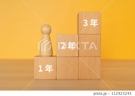 1年、2年、3年の文字が入ったブロックと人形 112923245