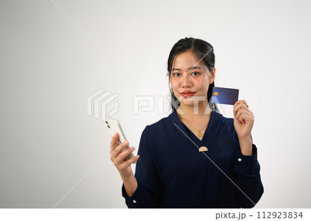 Attractive young woman holding credit card and mobile phone isolated on white background Attractive young woman holding credit card and mobile phone isolated on white background 112923834