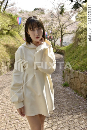 サクラ咲く公園でポーズをとる若い女性 112925154