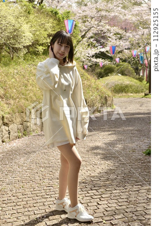 サクラ咲く公園でポーズをとる若い女性 112925155