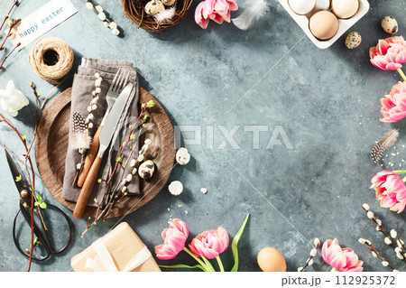 Easter table setting with spring flowers and cutlery on dark blue background top view flat lay 112925372