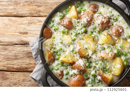 Creamed Green Peas And Potatoes with Parmesan closeup on the pan. Horizontal top view Creamed Green Peas And Potatoes with Parmesan closeup on the pan. Horizontal top view 112925601