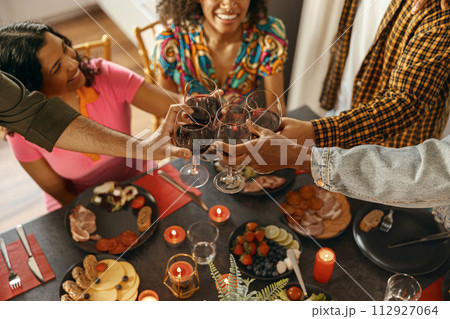 Close up of happy friends is drinking wine and clinking glasses having festive party at home Close up of happy friends is drinking wine and clinking glasses having festive party at home 112927064