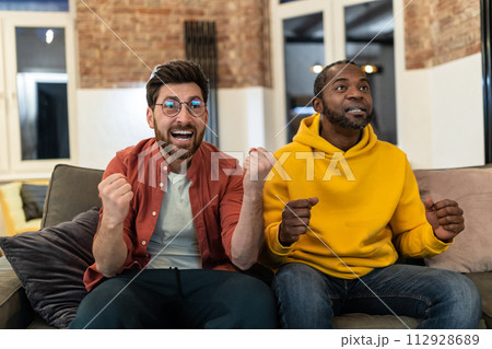 Two friends watching tv and looking excited and emotional 112928689