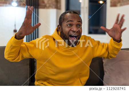 Dark-skinned man in yellow hoodie looking excited 112928741