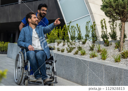 Male nurse in a blue doctors overall carrying a wheelchair Male nurse in a blue doctors overall carrying a wheelchair 112928813