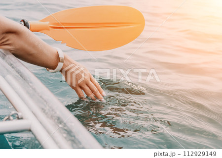 Woman in kayak back view. Happy young woman with long hair floating in transparent kayak on the crystal clear sea. Summer holiday vacation and cheerful female people relaxing having fun on the boat 112929149