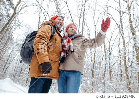 Mature couple in a snowy forest feeling excited 112929486