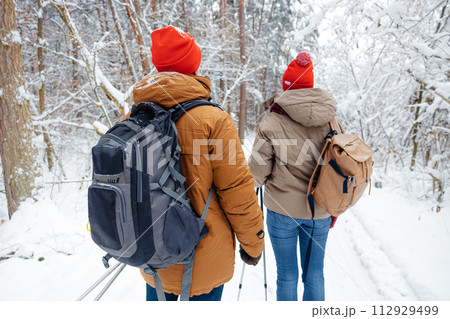 Two people with backpacks and scandinavian sticks in a forest 112929499