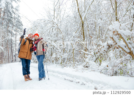Two people with backpacks and scandinavian sticks in a forest Two people with backpacks and scandinavian sticks in a forest 112929500