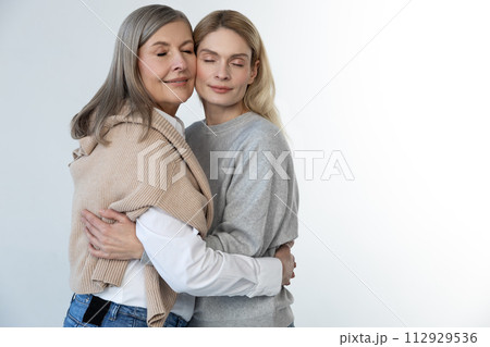 Mother and daughter standing together and looking relaxed 112929536