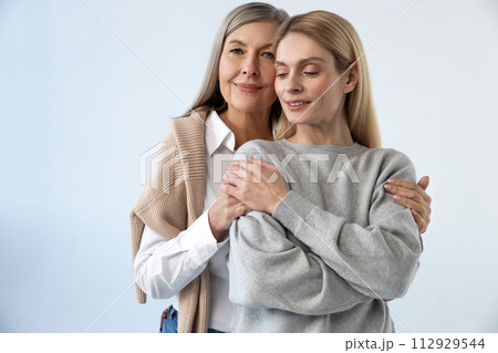 Mother and daughter hugging each other and looking peaceful Mother and daughter hugging each other and looking peaceful 112929544