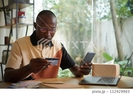 Black man paying for phone service with credit card 112929983