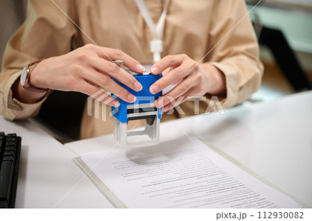 Hands of bank manager sealing document on desk Hands of bank manager sealing document on desk 112930082