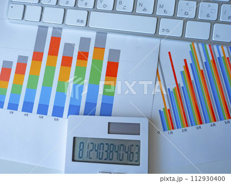 テーブルに置かれたグラフとキーボードと電卓 112930400