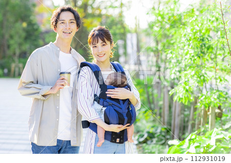 赤ちゃんを抱っこしながら外を歩く夫婦 112931019