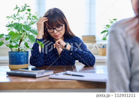 Mature sad woman in therapy session with mental professional 112931211