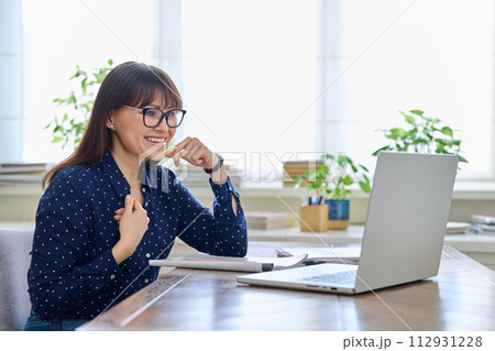 Woman teacher with textbook working online using computer 112931228