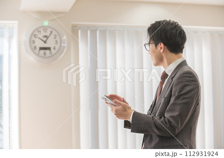 時間を気にするスーツ姿の男性ビジネスマン 時間を気にするスーツ姿の男性ビジネスマン 112931924