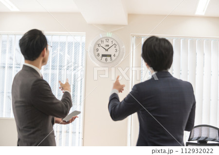 時間を気にするスーツ姿の男性ビジネスマン 時間を気にするスーツ姿の男性ビジネスマン 112932022