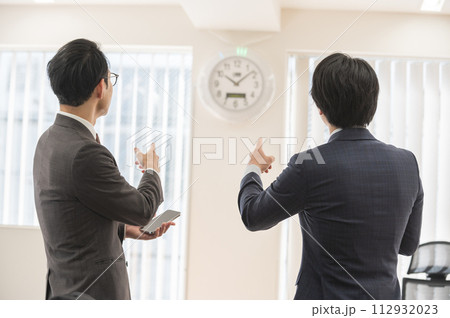 時間を気にするスーツ姿の男性ビジネスマン 時間を気にするスーツ姿の男性ビジネスマン 112932023