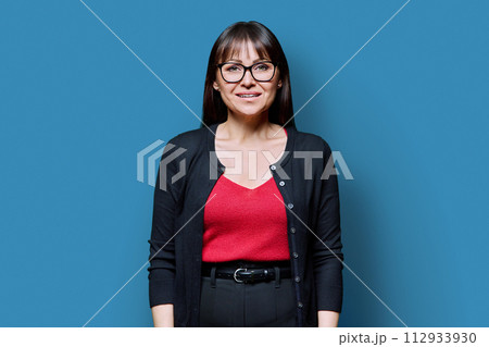 Smiling middle-aged woman on blue studio background Smiling middle-aged woman on blue studio background 112933930