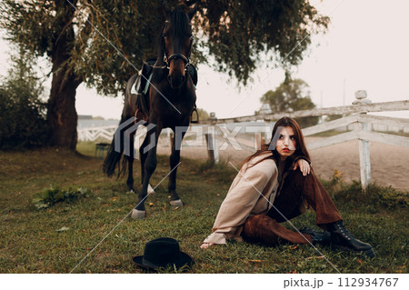 Cowgirl in brown clothes with her horse at outdoors ranch Cowgirl in brown clothes with her horse at outdoors ranch 112934767